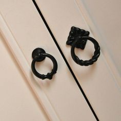 two pairs of black metal rings on the side of a white door with an iron handle