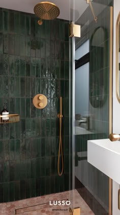 a green tiled bathroom with gold fixtures and shower head in the corner, next to a white sink