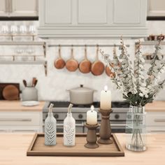 an image of a kitchen setting with candles and flowers in vases on the counter