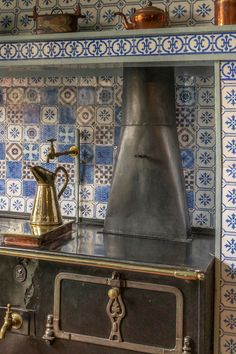 an old fashioned stove in a kitchen with blue and white tiles on the wall behind it