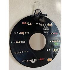 a black record with lots of earrings hanging from it's side on a wall