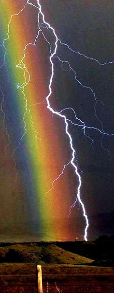 a rainbow is seen in the sky with lightning