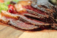 sliced up meat sitting on top of a wooden cutting board