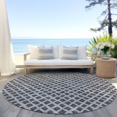 a white couch sitting on top of a wooden floor next to a table with flowers