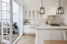 an open kitchen with white cabinets and marble counter tops, along with wooden flooring