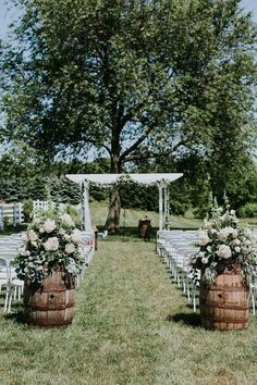 an outdoor ceremony setup with wooden barrels and flowers