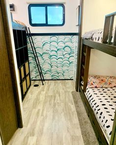 two bunk beds in a small room with wooden flooring and wall paper on the walls