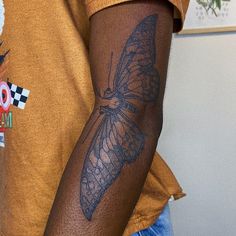 a close up of a person with a butterfly tattoo on his arm and the other arm behind him