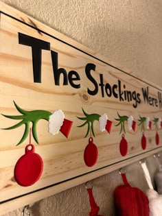 the stockings were hung on the wall with red and green ornaments hanging from it's hooks