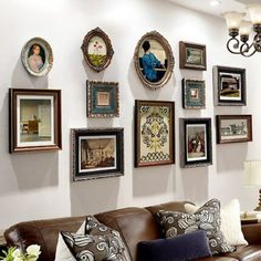 a living room filled with lots of framed pictures on the wall above a brown leather couch