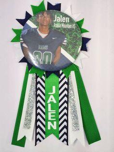 a green and white award ribbon with an image of jalen james mountain high school's football player