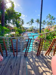 a pig is standing on a wooden deck next to a pool and palm trees in the background