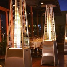 two tall metal lamps sitting next to each other on top of a wooden floor in front of a restaurant