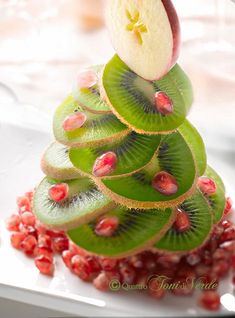 there is a christmas tree made out of kiwis and apples on the plate