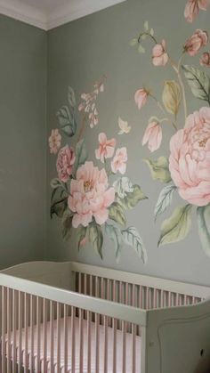 a baby's room painted with flowers on the wall and crib in the foreground