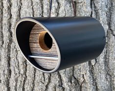 a bird feeder hanging from the side of a wooden tree trunk with no leaves on it