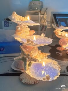 three seashells with candles on them sitting on a table