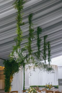 the tables are set up with white linens and greenery hanging from the ceiling