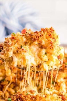 a close up of a piece of pizza with cheese and toppings on it, being lifted from the casserole dish