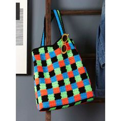 a multicolored crocheted bag hanging on a wooden rack next to a wall