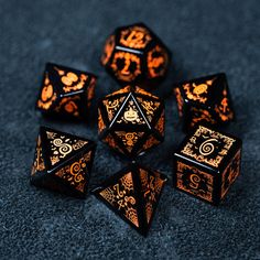 black and gold dice set with intricate designs on the sides, sitting on a dark surface