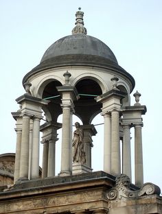 a clock tower with statues on the top and an arch in the middle above it