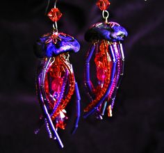 purple and red jellyfish earrings on a black background