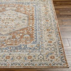 an orange and blue rug on the floor with wood floors in front of it,