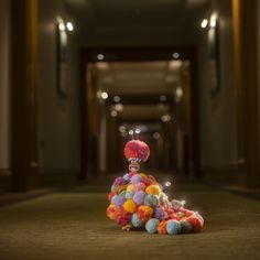 a stuffed animal sitting on top of a pile of pom poms in the middle of a hallway