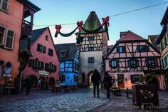 two people are walking down the street in front of some buildings with decorations on them