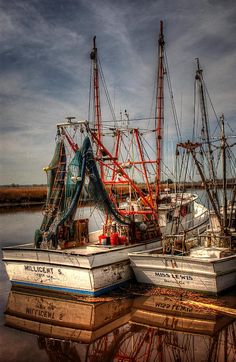 three boats are docked in the water on a cloudy day with dark clouds above them