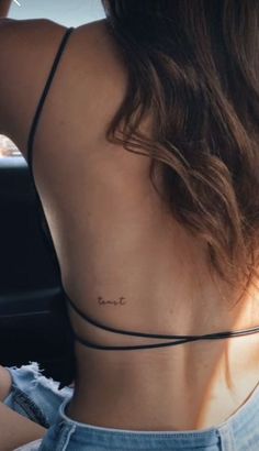 the back of a woman's neck with her name tattooed on it, sitting in a car