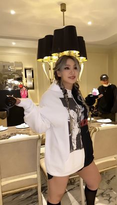 a woman standing in front of a chandelier wearing thigh high socks and boots