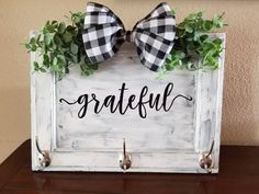 a wooden sign that says grateful with two bows on it and some greenery in the frame