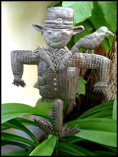 a metal sculpture of a man with two birds on his arm