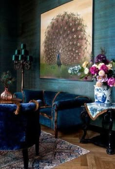 a living room filled with blue couches and chairs next to a painting on the wall