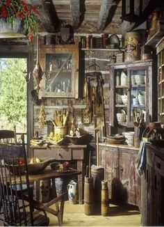 an old fashioned kitchen with lots of clutter on the table and chairs in it