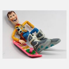 a toy figure laying on top of a pink skateboard next to another toy figure