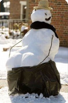 a snowman sitting on top of a bag in the snow