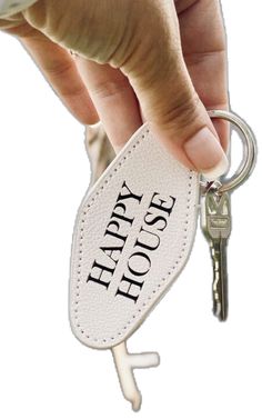 a hand holding a keychain with the words happy house on it's side