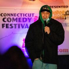 a man standing in front of a microphone with a green hoodie over his head