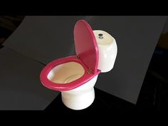 a white toilet with a pink seat and cover on it's back side, in front of a black background