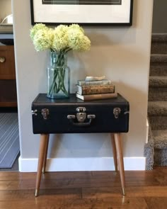 a black suitcase with flowers and books on it sitting in front of a stairway case