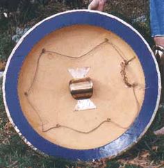 a person standing next to a blue and white frisbee in the grass with chains on it