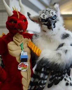 two stuffed animals dressed in costumes standing next to each other, one is white and the other is red