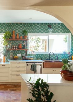 a kitchen with green and white wallpaper, potted plants on the counter top