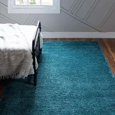 a bedroom with a blue rug on the floor and a bed in front of it