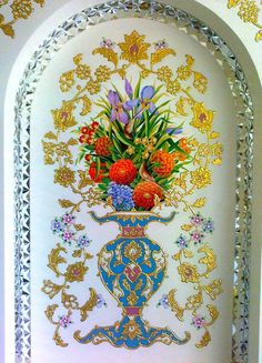 a vase filled with lots of flowers on top of a white wall next to a doorway