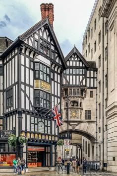 an old building with people walking in front of it on a rainy day and the british flag flying outside