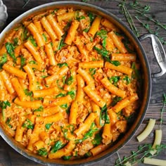 pasta with meat and spinach in a pan on a wooden table next to garlic